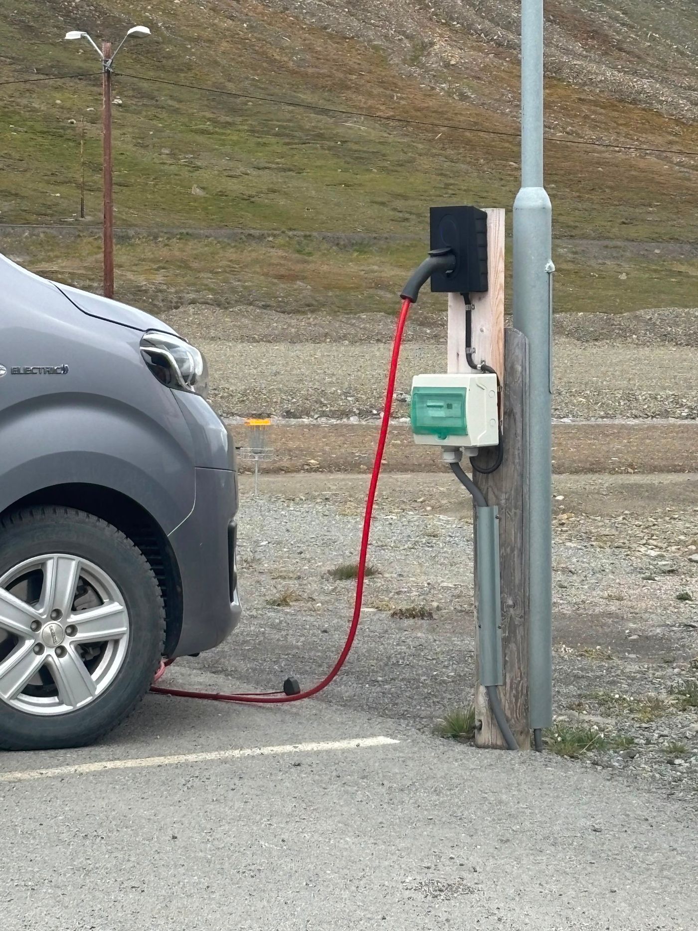 An electric van plugged in on the gravel at 78 north