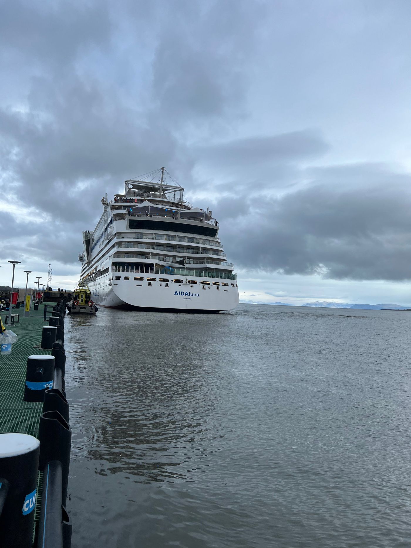 A cruise ship comes alongside in flat grey weather