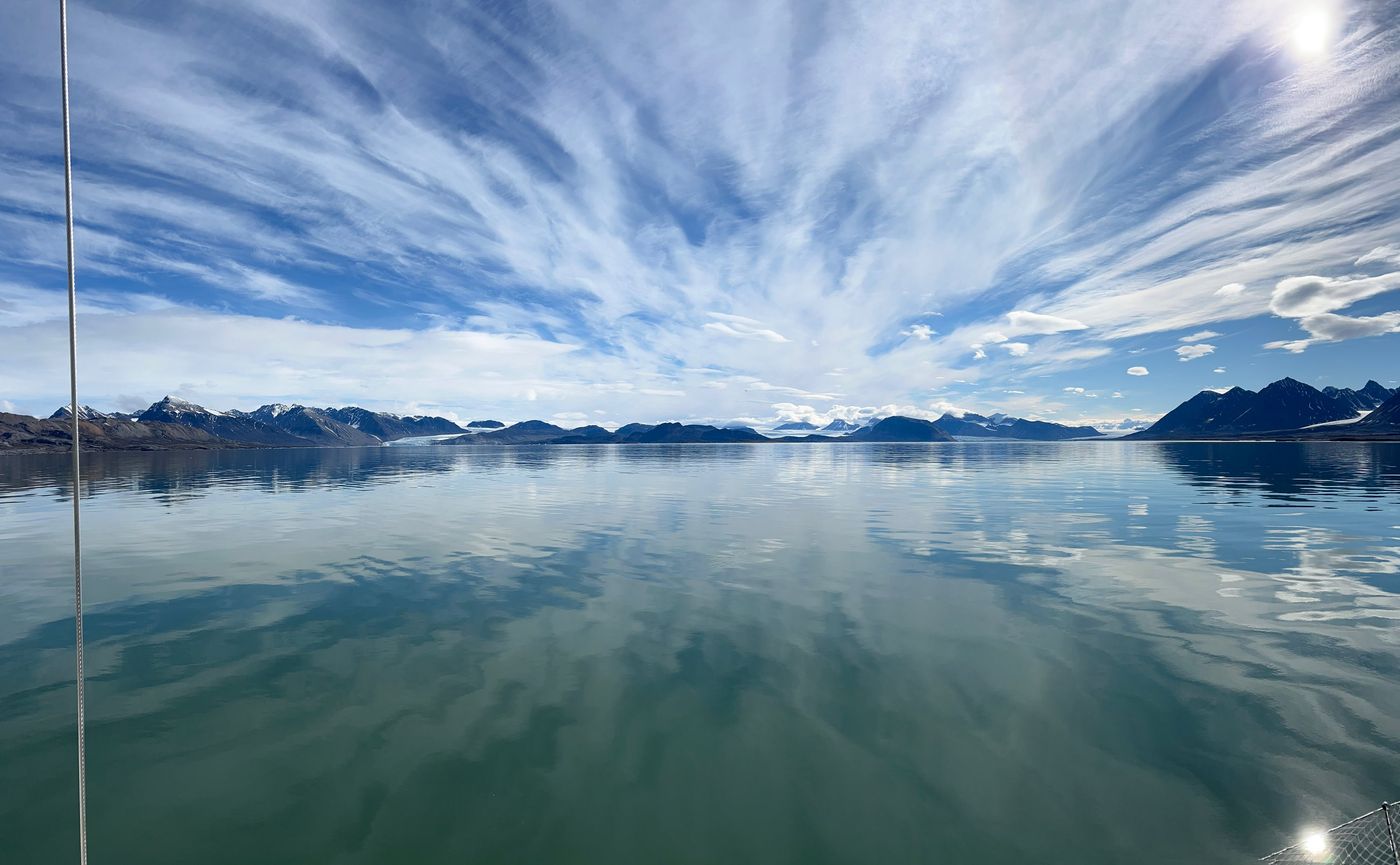 Cirrus fans out over a fjord like glass