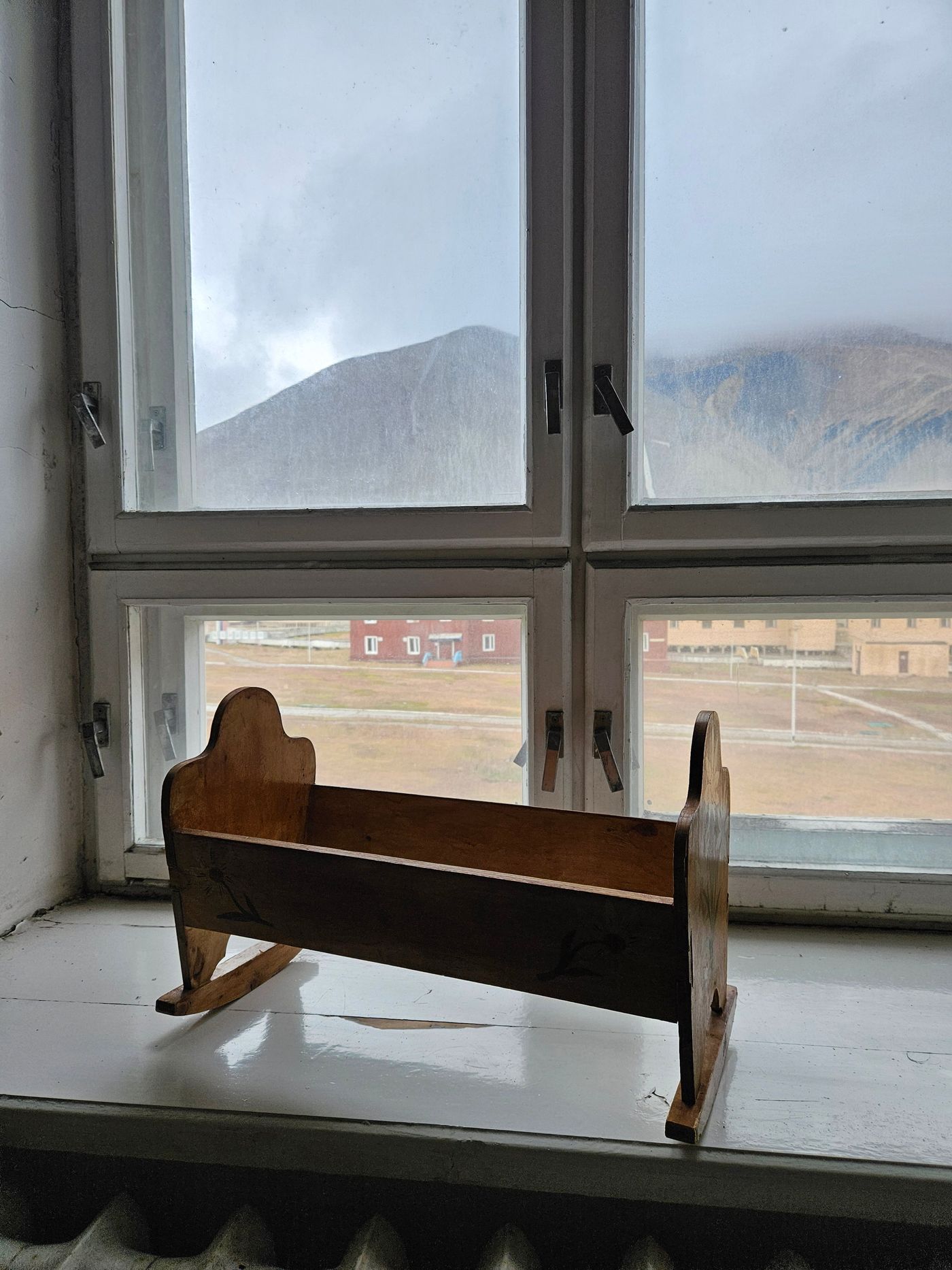 A child's cot on the sill, the mountain behind it