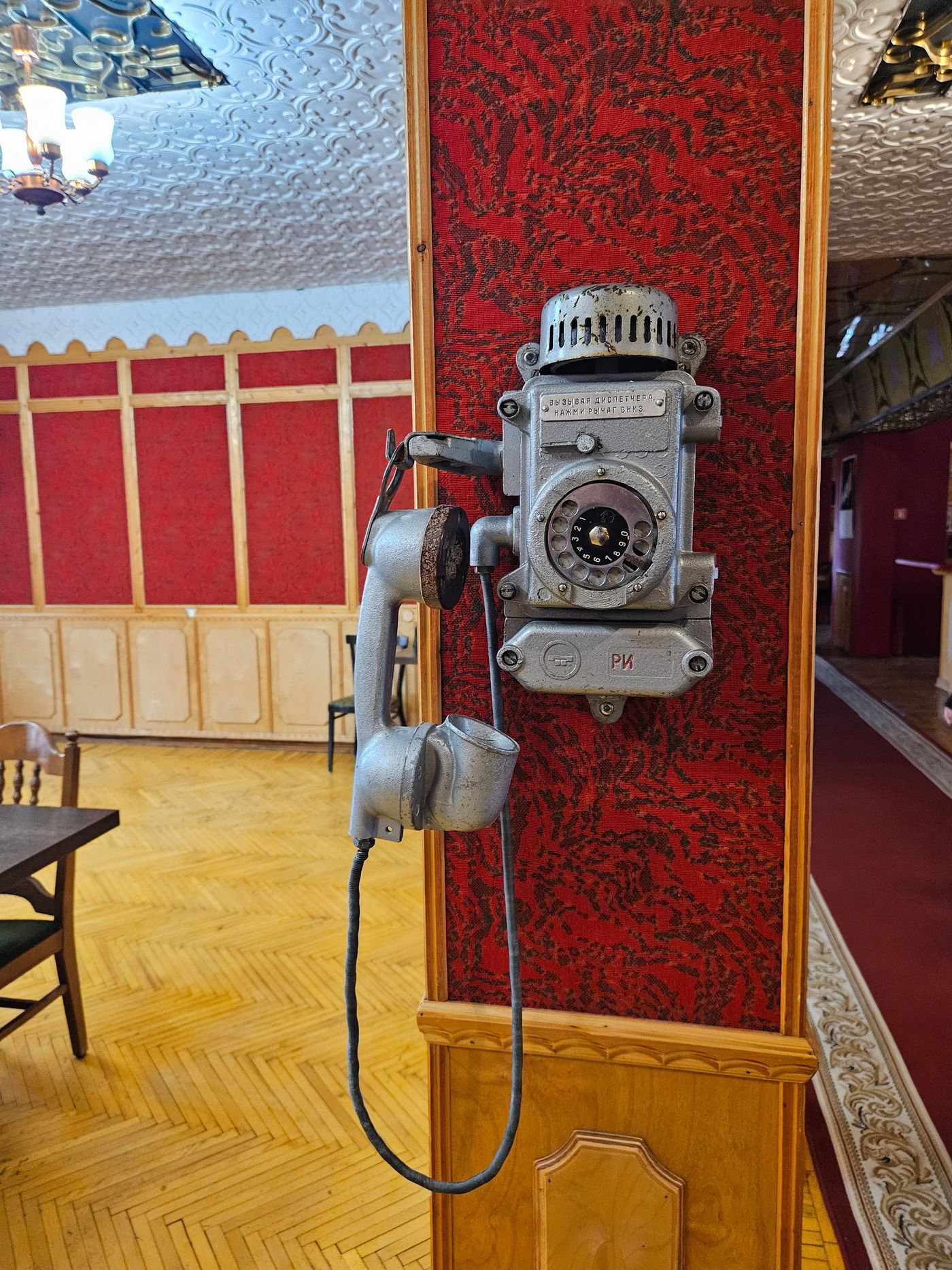 A wall telephone left on the red flock wallpaper