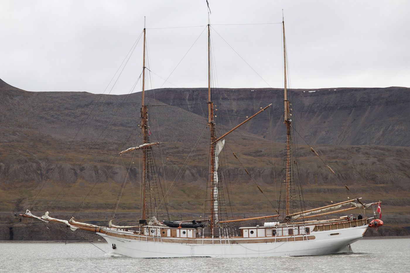 Schooner at anchor beneath the layered cliffs