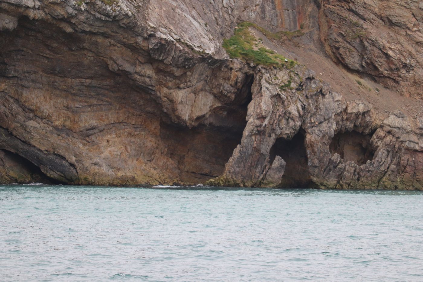 Twin caves in the cliff, turquoise water at the sill
