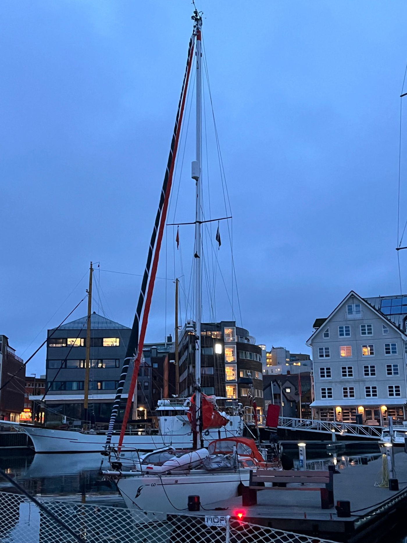Masts and lit quayside houses in the blue hour